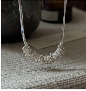 Macro shot of S925 silver necklace featuring a textured multi-ring pendant and snake chain