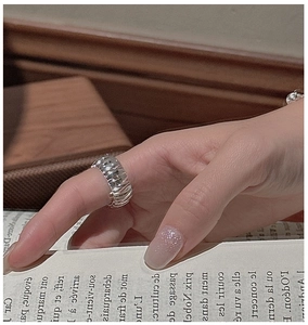 Detail of wide S925 silver vintage ring with textured wavy patterns on index finger