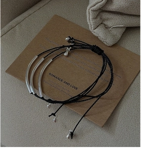 Close-up of three-layer S925 silver minimalist woven black cord bracelets with metal tubes
