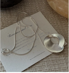 Close-up of S925 sterling silver stamp on matte geometric pendant necklace