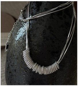 Detail of S925 sterling silver layered necklace with snake chain and ring pendant charms
