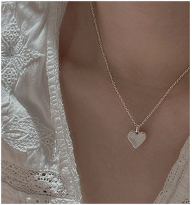 Gros plan du pendentif cœur mat sur chaîne en argent S925 avec tenue en dentelle