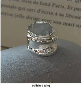 Detailed view of an irregular wavy wide band silver ring on a minimalist display stand