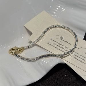 Italian-crafted silver snake bone bracelet with contrast gold clasp on ceramic plate