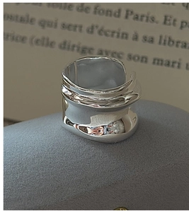 Detailed view of wide irregular lava texture silver ring on a grey stone pedestal