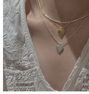 Gros plan de colliers à cœur dorés et argentés superposés pour un style bohème chic