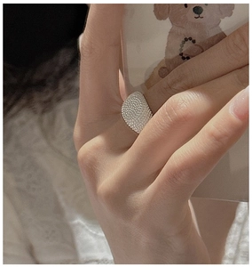 Close-up of wide S925 sterling silver ring with hammer-textured finish on a finger