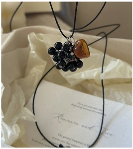 Macro detail of S925 silver grape necklace with black beads and amber heart pendant