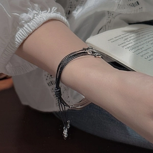 Minimalist triple-layer black cord silver bracelet shown on model with lace sleeve