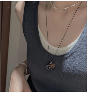 Detail of a vintage black grape-shaped necklace with heart pendant on a knitted sweater