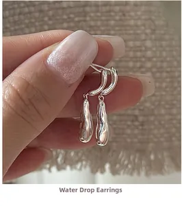 Detail shot of silver teardrop earrings with a polished mirror finish held by hand