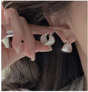 Detailed view of silver hoop earrings featuring a unique textured wavy surface design