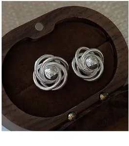 Detailed shot of S925 sterling silver floral spiral earrings in a vintage wooden jewelry box