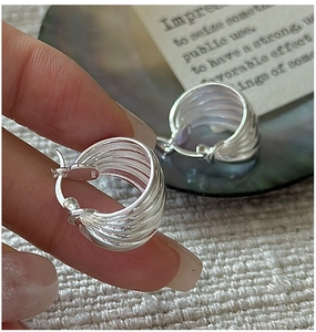 Macro detail of S925 sterling silver hoop earrings with vintage wavy texture and polished finish