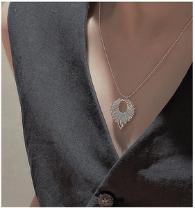 Detail of silver textured ring pendant on delicate bead chain necklace worn by model