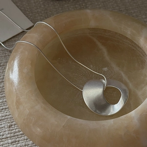 Minimalist S925 sterling silver necklace with matte twisted pendant on marble display