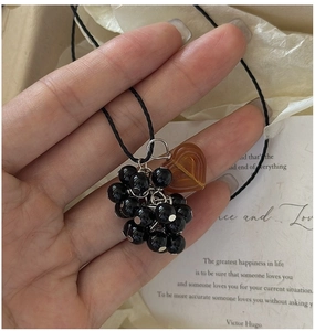 Detail of S925 silver grape pendant necklace with black beads and a heart-shaped charm