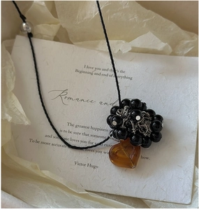 Detail of vintage silver necklace with black beads and amber heart pendant on art paper