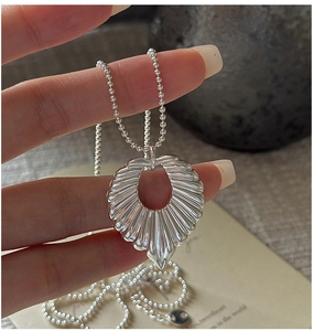 Macro shot of silver hollow leaf pendant with textured radial ridges on bead chain