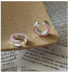 Macro shot of silver S925 ear cuffs with pink enamel glaze finish on cork background
