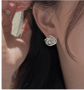Detail shot of silver rose stud earrings with twisted lines on a model ear