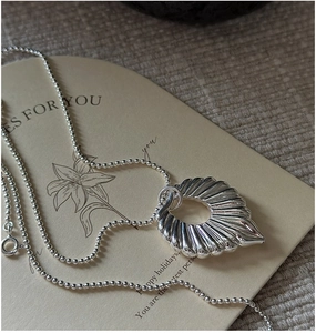 Detail of S925 sterling silver hollow pendant on bead chain against vintage floral card