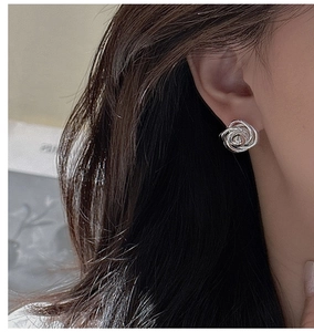 Macro detail of a 925 sterling silver twist knot stud earring worn by a model