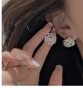 Macro detail of S925 sterling silver rose-shaped stud earrings with twisted bead textures