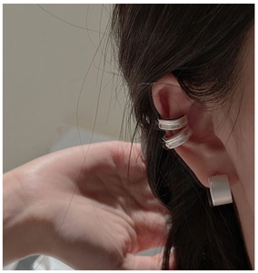 Detail of matte silver ear cuff and square stud earring set on a model's ear