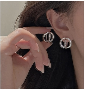 Close-up of a model wearing minimalist silver hollow geometric sphere stud earrings
