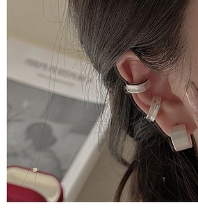 Close-up of three matte silver ear cuffs stacked on a model's ear without piercings