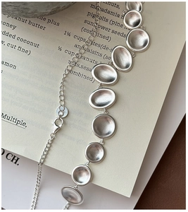 Detailed macro shot of S925 sterling silver necklace featuring oval matte metal charms
