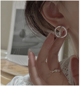 Detail of silver geometric hoop earrings on model with vintage office background