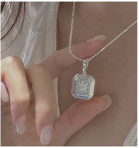 Detail of S925 silver starburst rectangle pendant with a textured edge on a rope chain