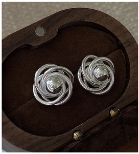 Macro shot of S925 sterling silver twisted coil earrings on a premium wood jewelry box