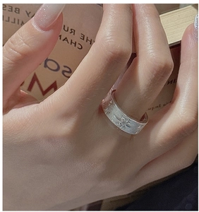 Macro shot of silver ring with brushed finish and star engraving on the finger