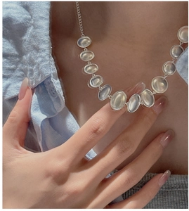 Close-up of S925 silver necklace with oval translucent stones on a model neck