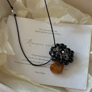 Retro S925 silver necklace with amber heart pendant and black beads on white paper