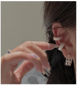 Detail of silver minimalist ear cuffs and hollow double-ring clips on a model ear
