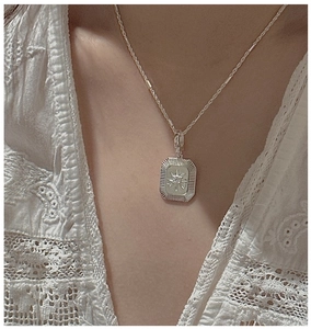 Detail of S925 sterling silver starburst pendant necklace worn on a lace outfit