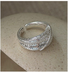 Close-up of S925 sterling silver ring with woven mesh texture on brown stone background