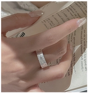 Detail of brushed S925 silver star ring worn by a woman over a vintage book background