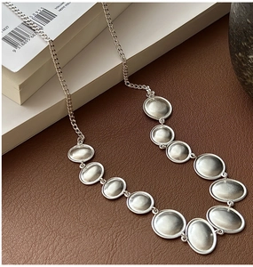 Close-up of S925 sterling silver necklace with matte oval discs on leather background