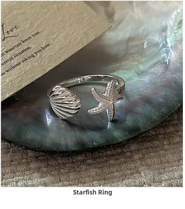 Macro shot of silver starfish and seashell ring on a shimmering mother-of-pearl base