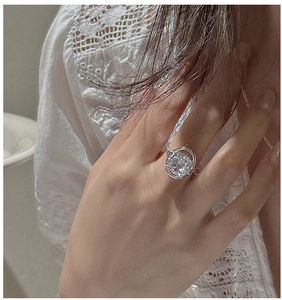 Detailed view of S925 silver ring with white crystal on a hand with lace background
