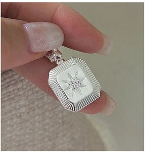 Macro detail of S925 sterling silver starburst pendant with engraved radial patterns