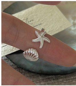 Close-up of S925 sterling silver ring featuring starfish and shell charms on finger