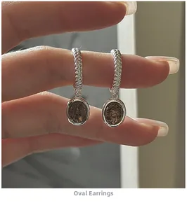 Detail of vintage S925 silver oval earrings with dark hair crystal and braided hoops