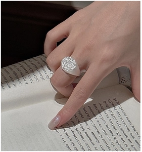 Detailed close-up of a vintage S925 sterling silver rose ring worn on a hand over a book