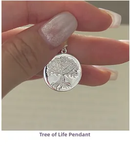 Detail of S925 sterling silver Tree of Life pendant held by hand showing fine relief work